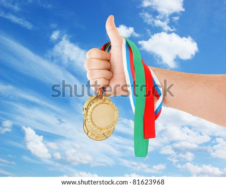 Gold medals in hand on sky background