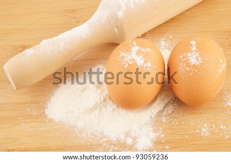 Flour with eggs with rolling pin on wooden board