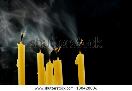 Yellow candles with smoke on black background