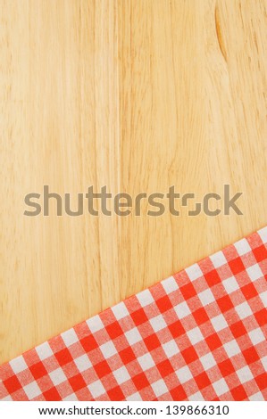 Red checked tablecloth on wooden table background