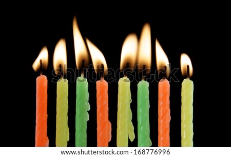 Eight burning candles on black background