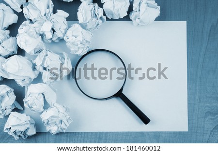 Empty paper, magnifying glass and crumpled paper