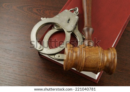 Judge\'s gavel and handcuffs on red legal book