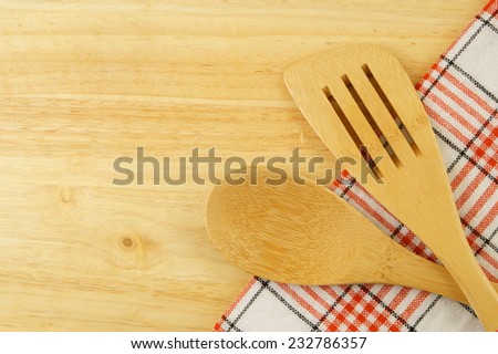 Tablecloth, spatula and spoon on wooden table background, cooking concept