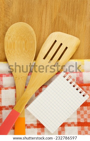 Tablecloths, spatula, notebook and spoon on wooden table background