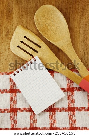 Tablecloth, spatula, notebook and spoon on wooden table background