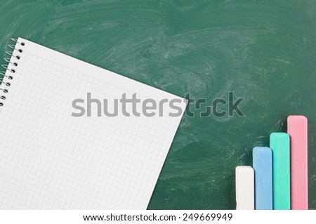 Green school board with color chalk and blank checked note paper for text