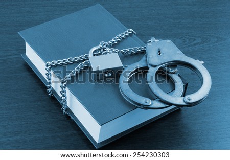 Information security concept, handcuffs, book with chain and padlock