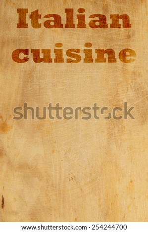 Old grunge wooden kitchen cutting board as background with words italian cuisine