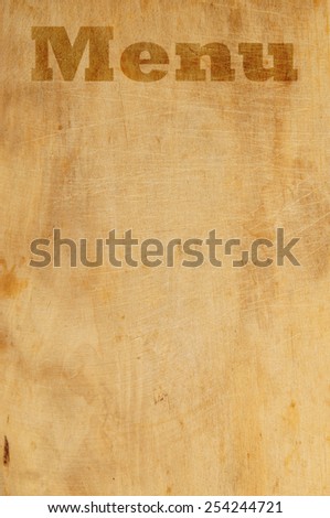 Old grunge wooden kitchen cutting board as background with word menu