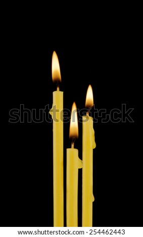 Yellow burning candles isolated on black