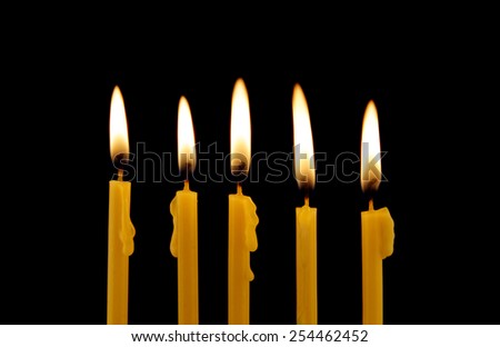 Yellow burning candles isolated on black