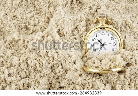 Old golden watch buried in sand