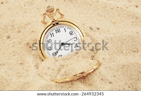 Old golden watch buried in sand