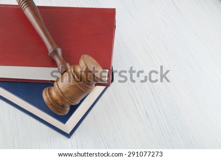 Wooden judge gavel and blue and red legal books on wooden table with copy space