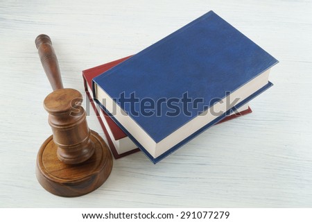 Judge\'s gavel and blue and red legal books on wooden table