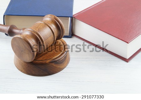 Judge\'s gavel and blue and red legal books on white background