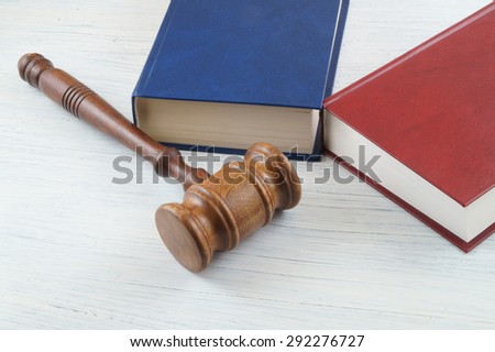 Wooden gavel and blue and red legal books on table