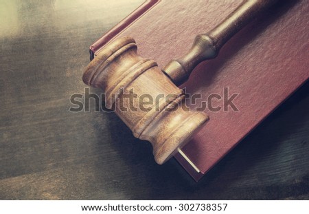 Wooden judge gavel and red legal book on wooden table