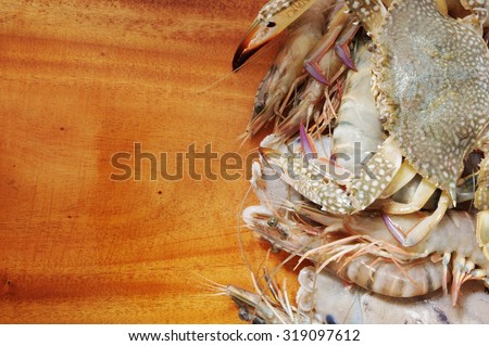Fresh seafood on wooden background with room for text, fresh squids, crabs and shrimps mixed together