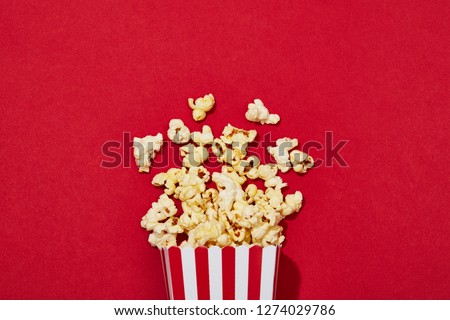 Full of popcorn in classic striped box on color background