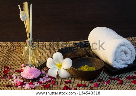 thai spa aroma setting  with aroma reed diffuser, spa mud, bath salt on spoon, frangipani, towel and rose patals