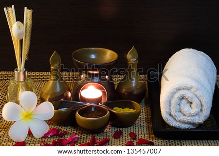 Spa massage setting with towel, frangipani, rose petals, aroma reed diffuser and spa mud
