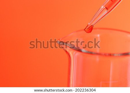 Pipette adding red fluid to test tubes on red light background
