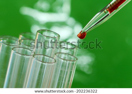 Pipette adding red fluid to test tubes on green background