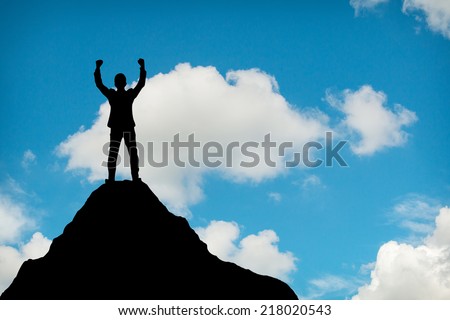 Silhouette of businessman hold up hands on the peak of mountain,success concept