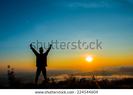 silhouette of man hold up hands at sunrise