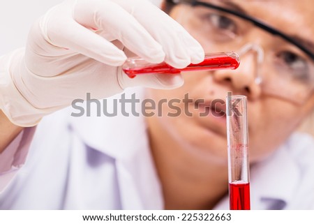 science laboratory worker adding red solution into test tube