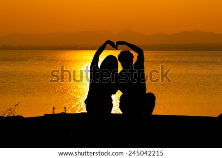 Silhouette of couple in love,Love sensuality and valentine day concept man and woman make heart sign  love at lake side