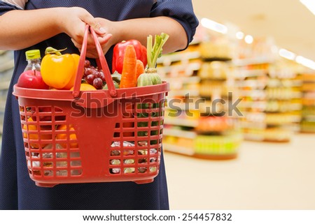 woman holding shopping basket in supermarket