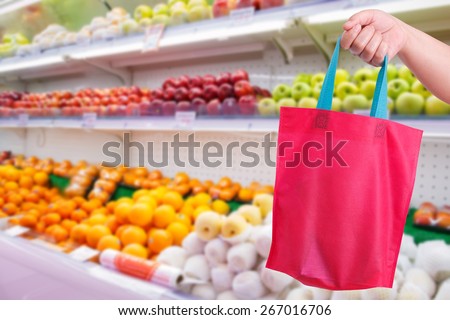 closeup hand holding reusable bag in supermarket
