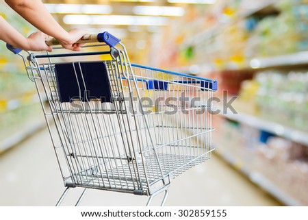 closeup hand pushing shopping cart in groceries store