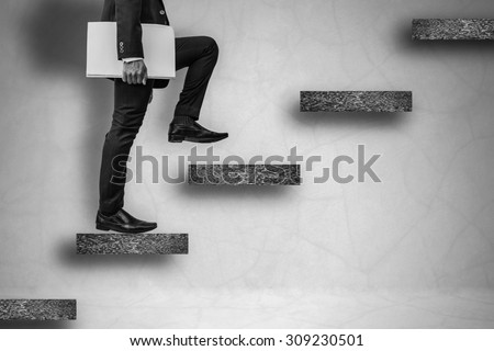 back and white businessman holding files climbing stairs on concrete wall