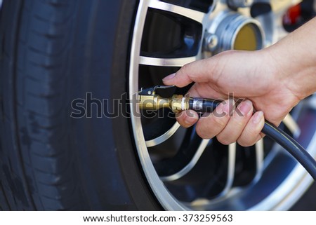 driver checking air pressure and filling air in the tires close up