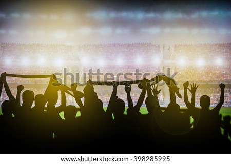 Silhouettes of soccer or rugby supporters in the stadium during match