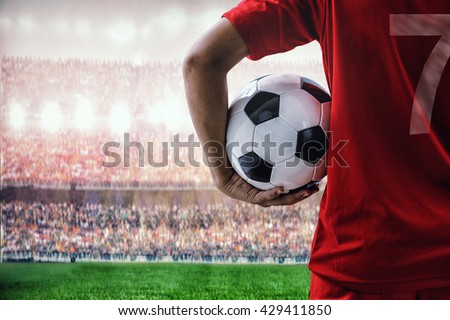 soccer football player in red team concept holding soccer ball in the stadium