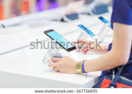 woman choosing a new mobile phone in a shop focus on a smart phone