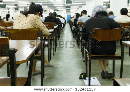 Students sitting in an exam hall doing an exam in university