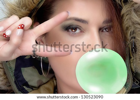 Fashionable hip hop woman in camouflage hoodie with green bubble gum