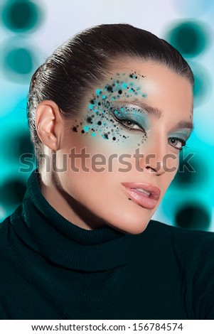 Beautiful Face of Fashion Girl with Small Green Fantasy Makeup, Looking at the Camera Sensually on an Abstract Green and White Background.
