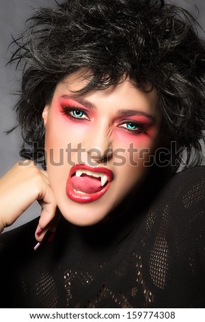 Vampire. Beautiful young woman with fancy makeup, fangs and wolf lenses