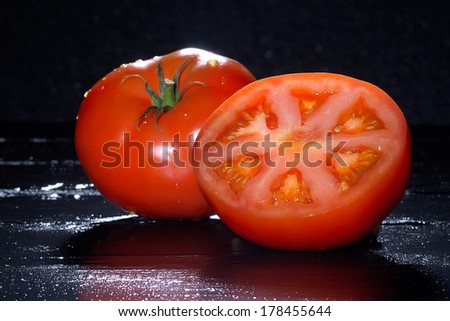 Close up Fresh Whole and Slice of Red Tomatoes on Wooden Black Table with Black Background. Vitamins. Clean eating diet concept