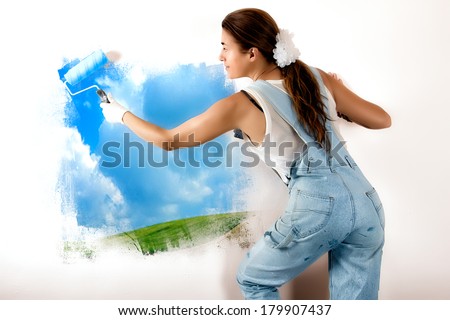 Young woman painting a nature landscape on wall with roller. Mural painting on wall. Ecologist