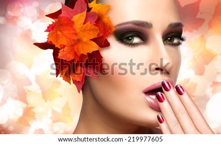 Autumn makeup and nail art trend. Fall beauty fashion girl. Professional makeup and manicure. Closeup portrait on autumnal background with falling leaves
