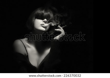Stylish sensual young woman with trendy fringe smoking a cigarette. Short hairstyle. High fashion portrait in black and white with copy space for text.