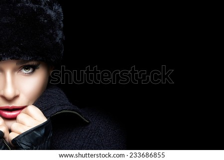 Winter Beauty Fashion. Close up of gorgeous young woman wearing trendy fur hat and mittens looking at camera sensually. High fashion portrait Isolated on black with copy space for text. Wintry style
